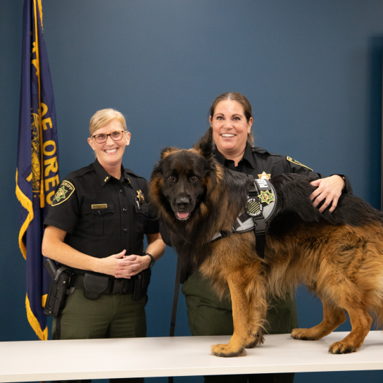 Sheriff, deputy, and Comfort dog pose for a photo.