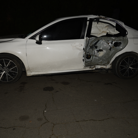 a white toyota camry with body damage parked on a street